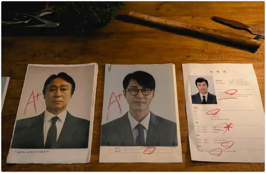 桌面上摆放的求职简历和证件照,红笔标记显示求职过程,暗示主角面临的就业困境