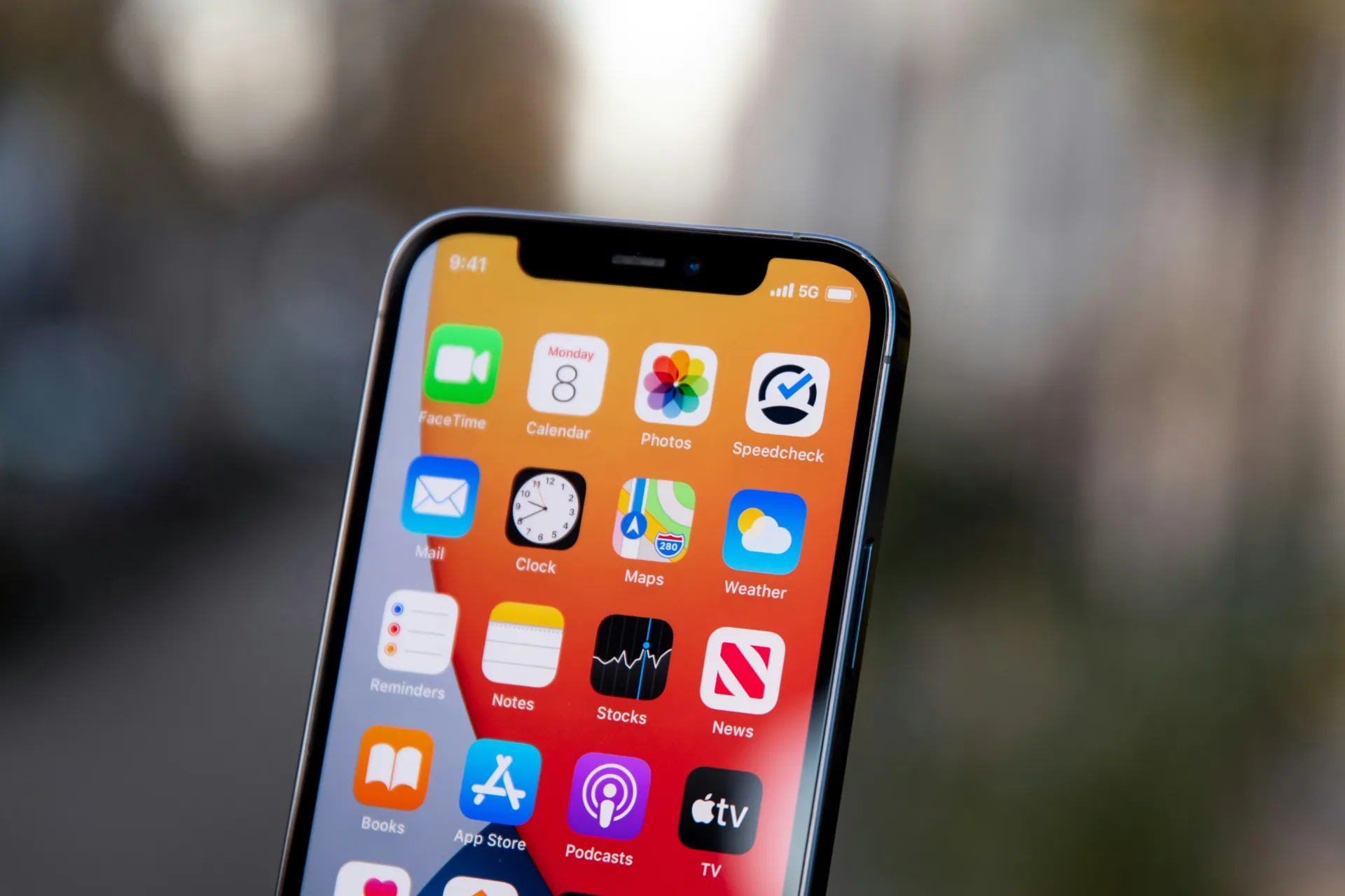 iPhone 屏幕上的 App 图标特写，包括天气、地图、相册、邮件等常用应用，背景虚化